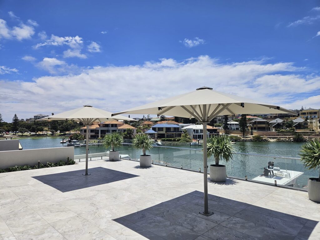 Ultrashade umbrella shading an outdoor seating area by the water