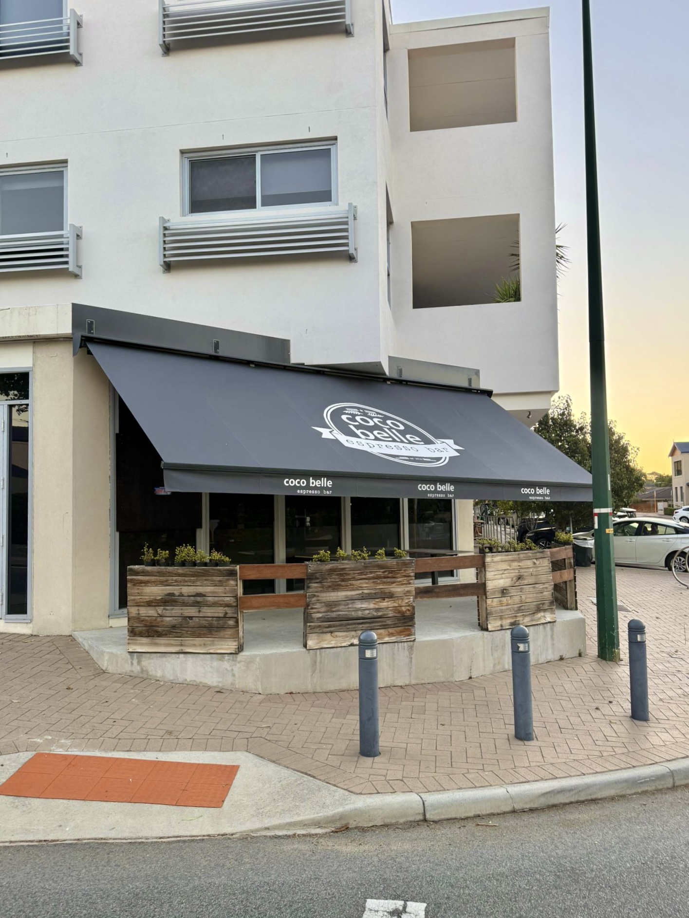 Commercial folding arm awning with custom branding installed at a Perth cafe